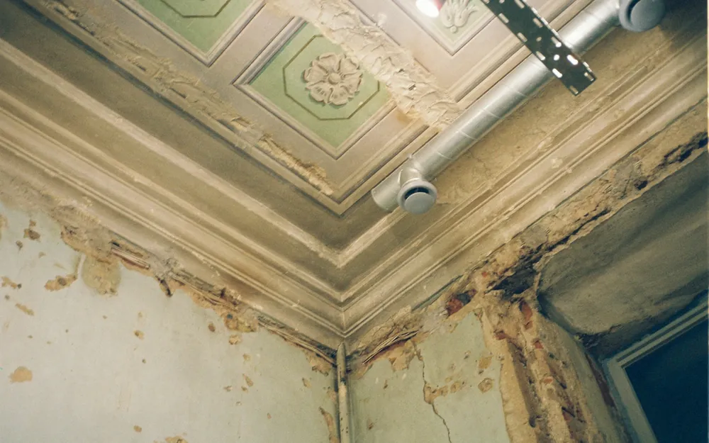 Esquina de un cielo antiguo con manchas y pintura soltada por la humedad