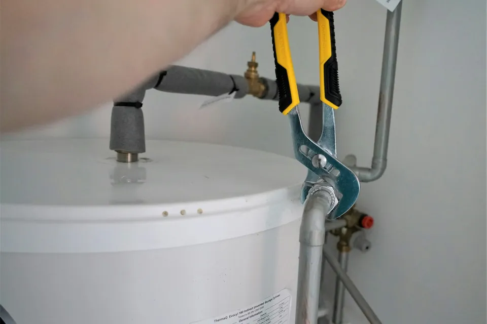 Llave de gasfíter ajustando las conexiones de un termo de agua caliente