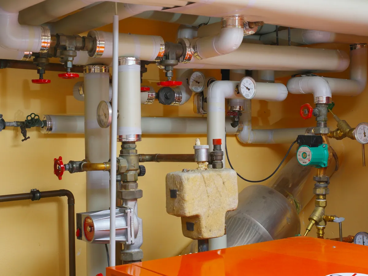 Caldera con cañerías, válvulas y manómetros en una sala técnica